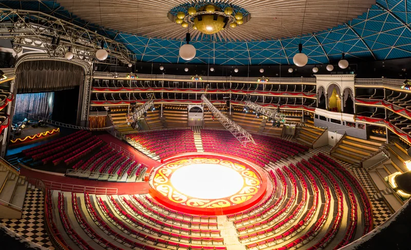 Interior of the Coliseu dos Recreios with the lit circus ring at the centre, red seating and the blue dome